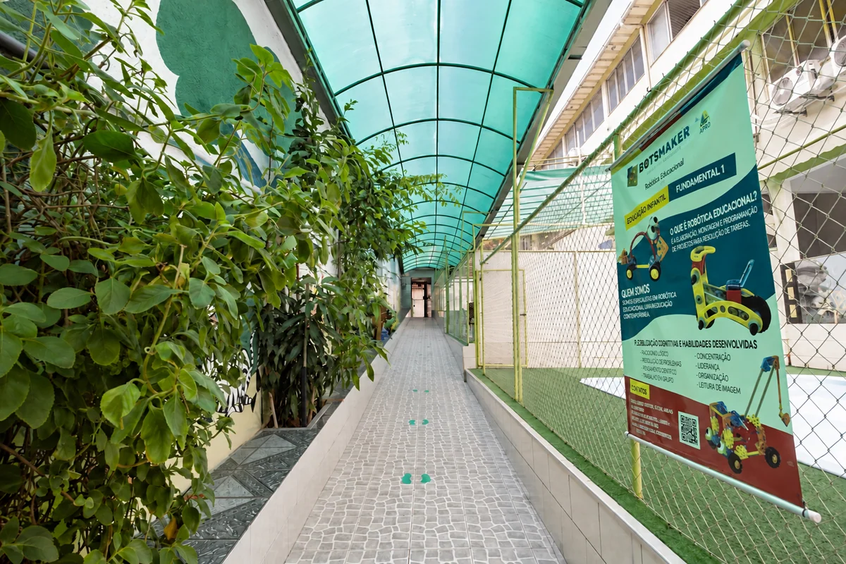Corredor de entrada coberto, com plantas ao lado da quadra