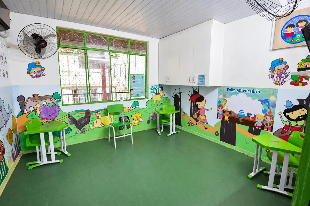 Sala da Educação Infantil com mesas pequenas e murais