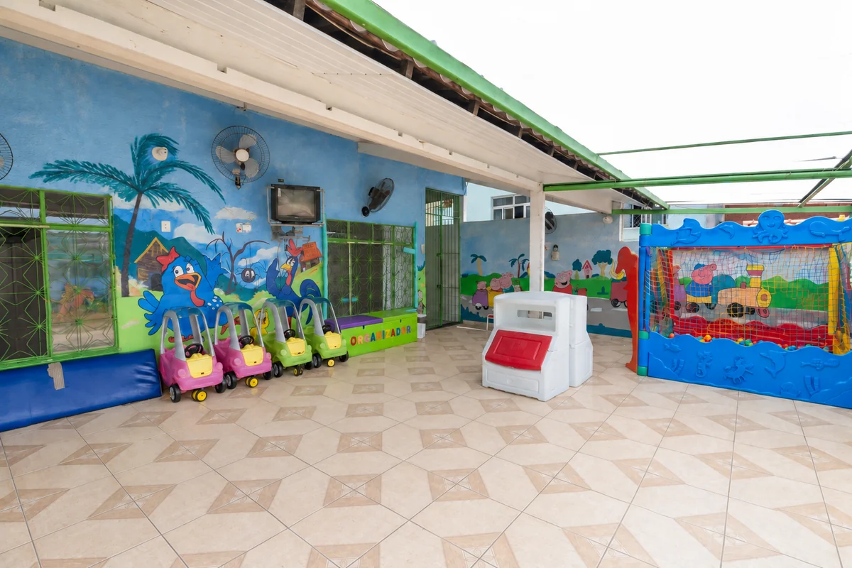 Pátio com brinquedos, carrinhos e murais coloridos