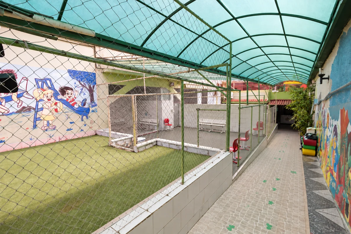 Quadra coberta da escola, com grama sintética e traves